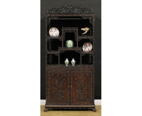 A Chinese hardwood open porcelain vitrine, shaped pediment pierced and carved with scrolling leaves above an arrangement of s