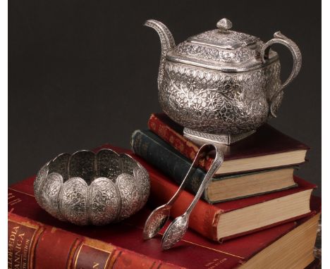 An Indian silver teapot, profusely chased with scrolling foliage, probably Kutch, 12cm high; a similar lobed sugar basin and 