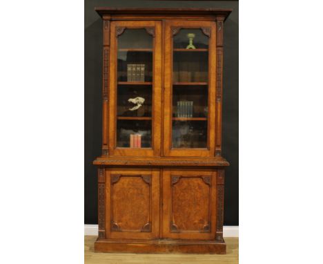 A late Victorian Aesthetic Movement period oak library bookcase, outswept cornice above a pair of glazed doors enclosing thre