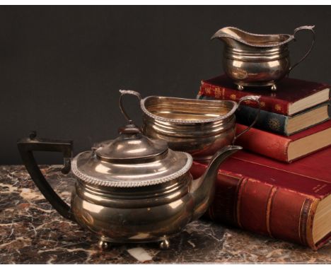A George V silver three piece boat shaped tea service, comprising teapot, sugar basin and cream jug, Goldsmiths &amp; Silvers