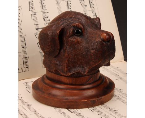 A large Black Forest novelty inkwell, carved as the head of a dog, hinged cover, glass eyes, turned circular base, 14.5cm dia