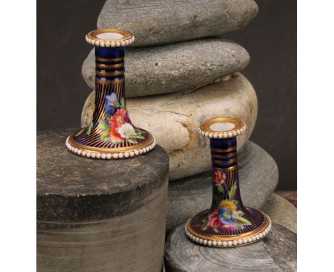 A pair of Spode flared miniature candlesticks, finely painted in coloured enamels with flowers and leaves, on a blue and spir