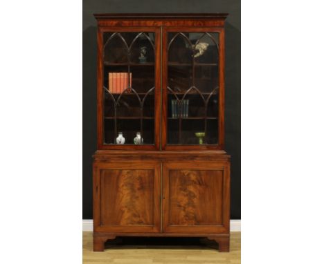 A George IV mahogany library bookcase, moulded cornice with dentil capital above a pair of astragal glazed doors enclosing si