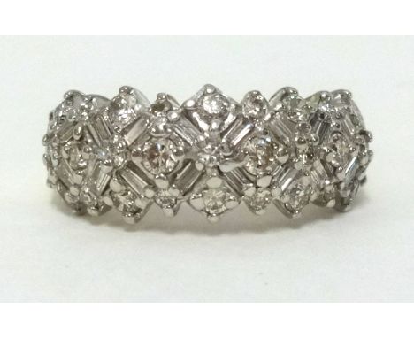 A 14ct diamond set band ring with an arrangement of baguette and round cut diamonds, finger size M.