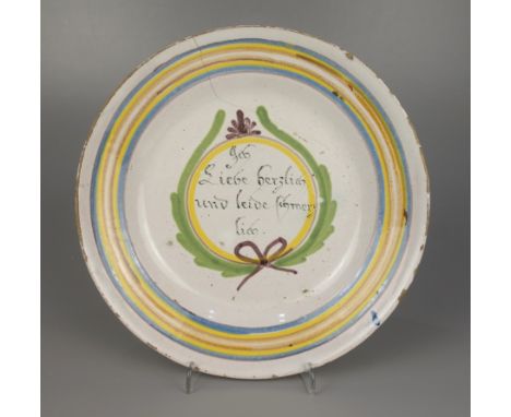 Fayenceteller mit Spruch, Schrezheim, 18.Jh., Scharffeuerfarben, Fahne mit gelb-braunen-hellblauen Streifen, "Ich liebe herzl