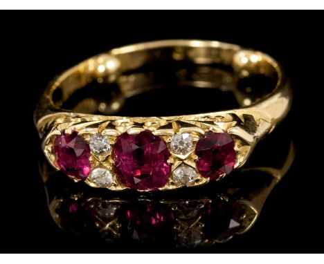 Late Victorian ruby and diamond ring with three oval mixed cut rubies interspaced by four old cut diamonds in carved gold cla