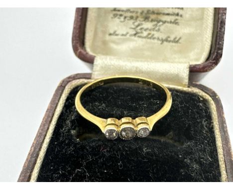 A Three Stone Diamond Ring, the graduated brilliant cut stones, collet set between slim tapering band stamped "18ct" "20 3" (