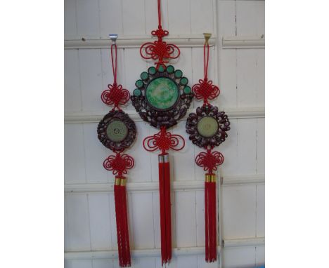 2 Carved jade wall hanging amulets with wood effect surrounds and red tassels along with a larger example with jade effect in