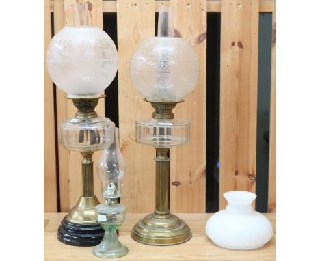 A lot of two brass oil lamps with reeded column bases, a glass based oil lamp and a spare milk glass shade (4) Condition Repo