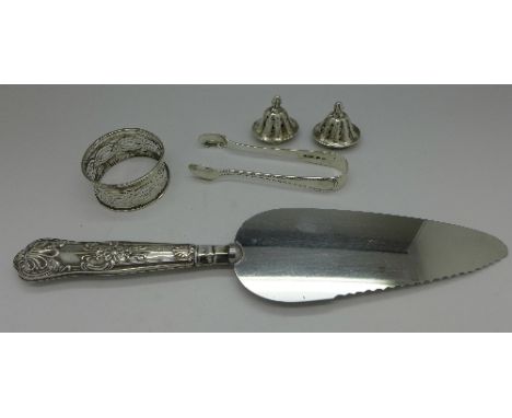 A pair of silver sugar bows, a silver napkin ring, a silver handled cake knife and two silver pepper tops, weight of silver 4