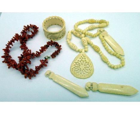 A carved ivory necklace, three ivory bookmarks, napkin ring and a coral necklace