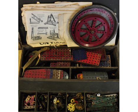 A quantity of early Meccano  contained in a black tin covered trunk with instruction booklet and related paperwork