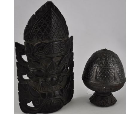 An carved ebony Thai mask, H. 31cm together with a heavy cast iron finial modelled as a pine cone