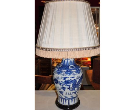 A Chinese blue and white baluster vase table lamp decorated with dragon motif with pleated silk shade