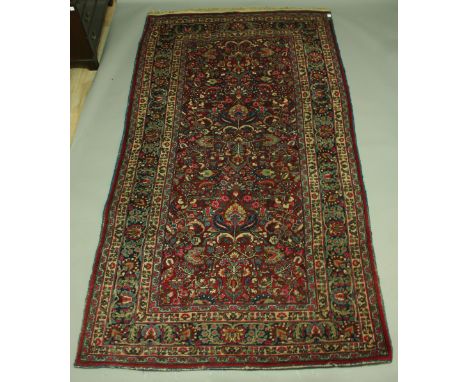 A PERSIAN CARPET, a central panel of stylised flowers and foliage inside a broad five strap border, 320 x 180cm