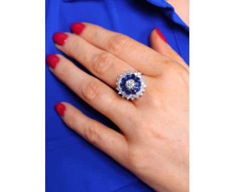 A Sapphire and Diamond Cluster Ring, claw set with modern round brilliant-cut diamond of approximately 0.50 carats, surrounde
