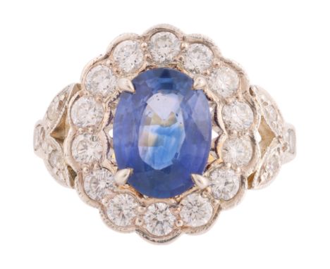 A Sapphire and Diamond Cluster Ring, the oval flowerhead cluster panel set with an oval mixed cut sapphire measuring approxim