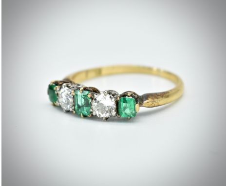 An 18ct gold emerald and diamond five stone ring. The ring set with two round brilliant cut diamonds and three step cut emera