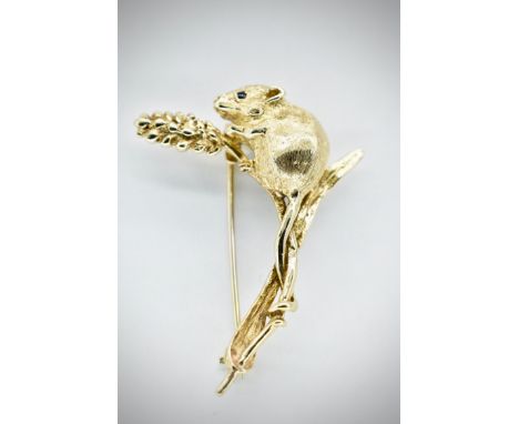 A hallmarked 9ct gold and sapphire figural brooch pin. The brooch in the form of a field mouse nibbling an ear of corn, havin
