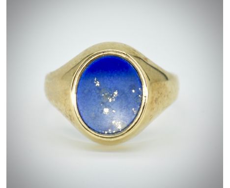 A hallmarked 9ct gold and lapis lazuli signet ring. The ring set with an oval bezel set lapis lazuli plaque to plain tapering