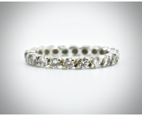 A French 18ct gold and diamond eternity ring. The ring set with 21 round brilliant cut diamonds in an oval 2 prong setting. P