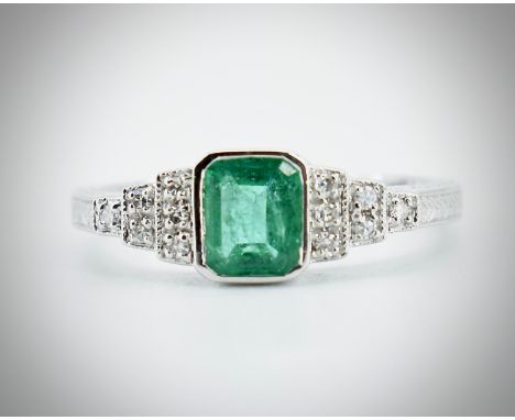 An 18ct white gold emerald and diamond ring. The ring in the Art Deco style being set with a central octagon cut emerald havi