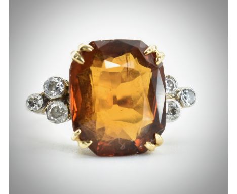 A 9ct gold citrine and diamond ring.&nbsp; The ring set with a mixed cut citrine flanked by 6 bezel set diamonds to plain sha