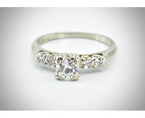 A 14ct white gold and diamond ring. The ring set with a central round brilliant cut diamond flanked by four single cut diamon