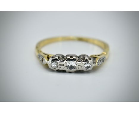 An 18ct gold three stone diamond ring. The ring having three round cut diamonds and diamond set cathedral shoulders. Marked 1