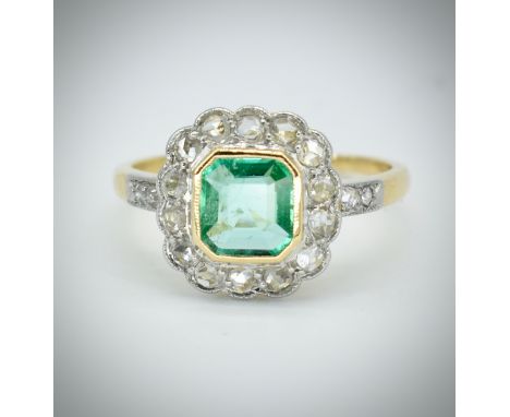 An 18ct gold emerald and diamond ring. The ring set with an octagon mixed cut emerald, framed by rose cut diamonds having ros