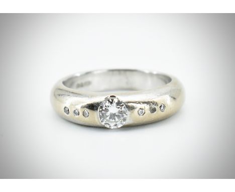 A hallmarked 18ct gold and diamond band ring. The ring set with a central round brilliant cut diamond having diamond accent s