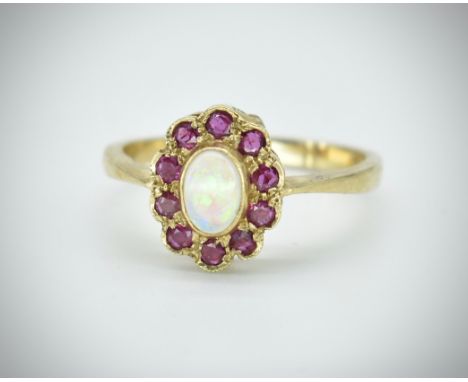 A hallmarked 9ct opal and ruby cluster ring. The ring set with a central oval opal cabochon surrounded by round mixed cut rub