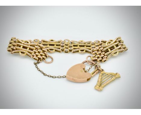 A Victorian 9ct gold mesh and weave linked bracelet adorned with a harp charm and a 9ct gold padlock. The bracelet with raise