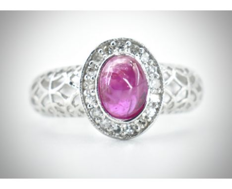 An 18ct white gold ruby and diamond ring. The ring set with a central&nbsp; ruby cabochon framed by single cut diamonds to a 