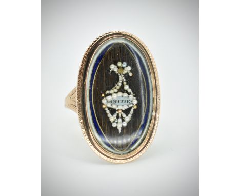 A Georgian gold navette memorial ring.&nbsp;The ring having a pearl set urn framing a plaque inscribed 'Amitte' laid upon a h