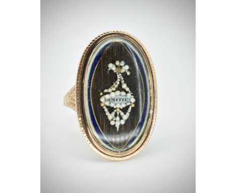 A Georgian gold navette memorial ring.&nbsp;The ring having a pearl set urn framing a plaque inscribed 'Amitte' laid upon a h