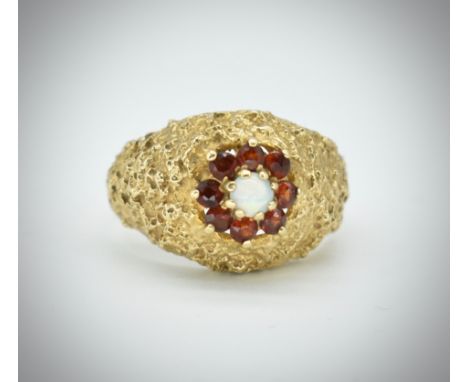 A 9ct gold opal and garnet dome ring. The ring set with a central opal surrounded by round cut garnets set within a textured 