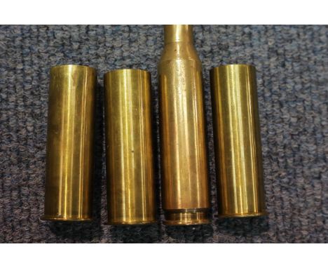 Three 27 mm brass cartridges marked K Limited and a machine gun bullet case. P&amp;P Group 1 (£14+VAT for the first lot and £