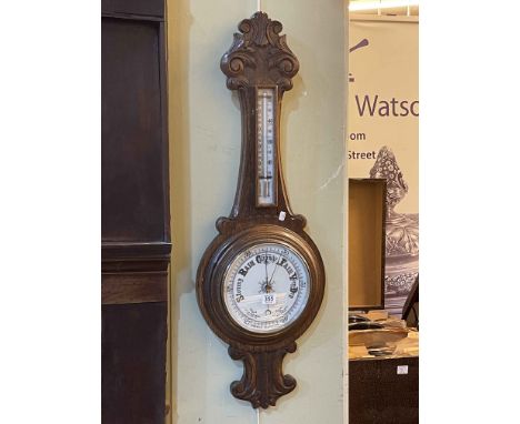Carved oak aneroid barometer with enamelled dial, 87cm.