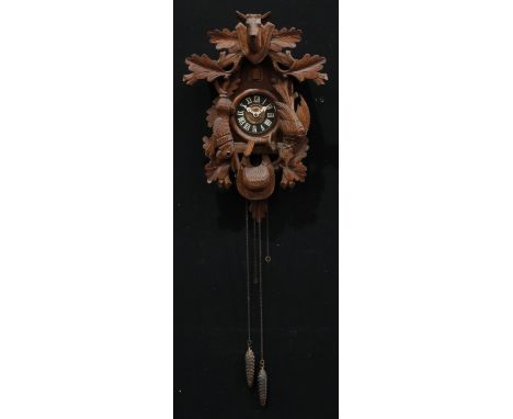 A Black Forest cuckoo clock, carved with a stag head and hanging game, 54cm high 