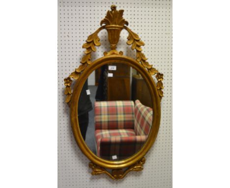 A Neo Classical style softwood and gesso oval mirror decorated with central urn finial and foliate swags 