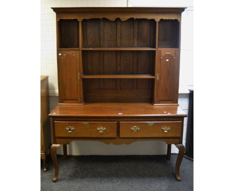 A mid-20th century oak dresser, ogee cornice over shaped frieze, two central shelves flanked by two cupboard doors both enclo