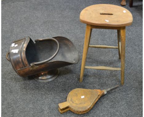 An early 20th century copper helmet shaped coal scuttle; a pair of fireside bellows; a 1970's beech school stool (3)