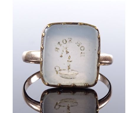 An unmarked yellow metal intaglio carved Bon Soir chalcedony panel seal ring, with chamber stick emblem, setting height 15.1m