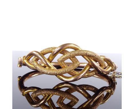 An early 20th century yellow metal hinged bangle, textured inter-woven settings, stamped A18C, internal diameter 59mm, intern
