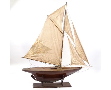 A 19th century wooden-hulled model pond yacht with masts and rigging, hull length 1.1m, on wooden stand, overall height 1.53m