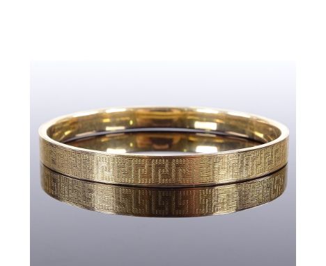 A 9ct gold slave bangle, engine turned Greek Key decoration, maker's marks MPG, hallmarks Birmingham 1924, band width 8.1mm, 