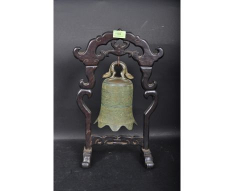 A vintage late 20th century Chinese Oriental bell on stand having a pierced carved hardwood frame. The bell has raised foliat