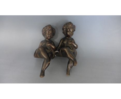 A pair of bronze figures of seated children - Height 12cm - good patina
