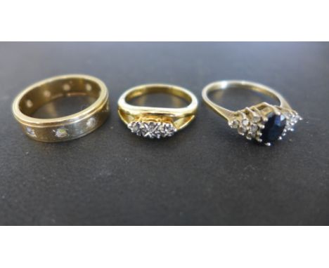 Three 9ct yellow gold rings, one sapphire and clear stone ring, the sapphire flanked by six clear stones in triangular settin